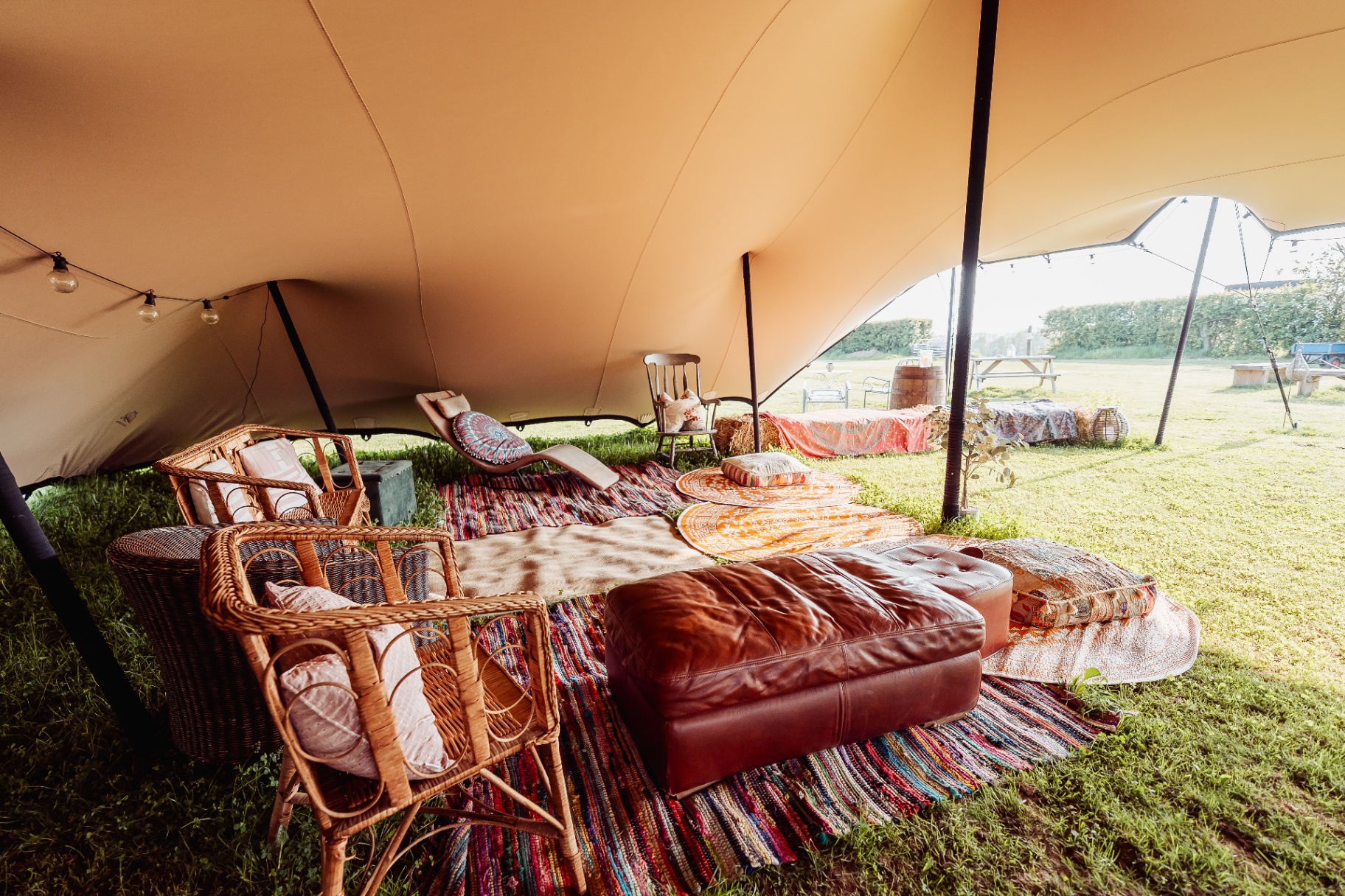Inside the stretch tent with rugs, cushions and rattan chairs